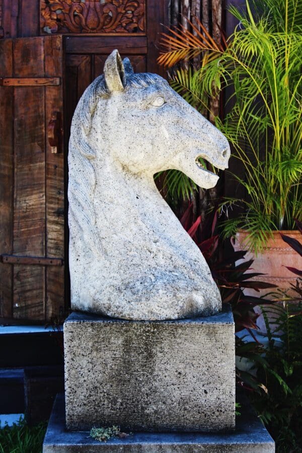 A statue of a horse 's head on top of a stone block.