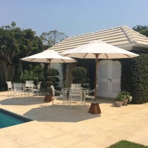 A pool with two umbrellas and chairs by the side of it.