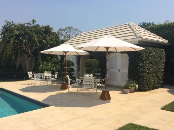 A pool with two umbrellas and chairs by the side of it.