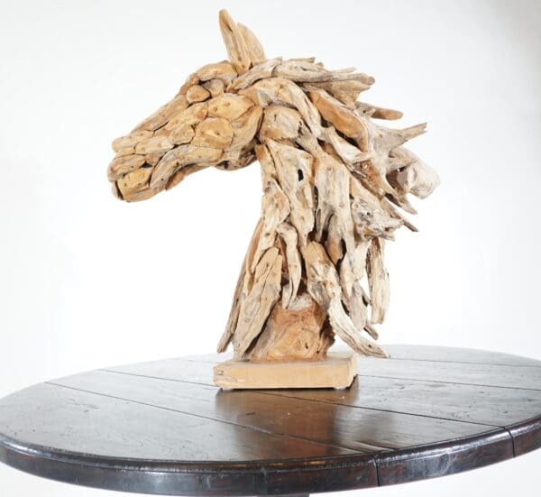 A horse head sculpture made of wood on top of a table.