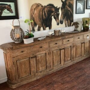 A large wooden buffet with two horses on the wall.