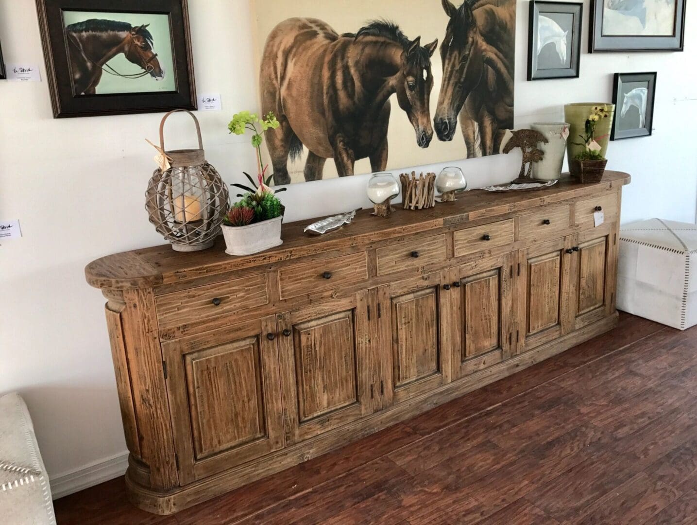 A large wooden buffet with two horses on the wall.