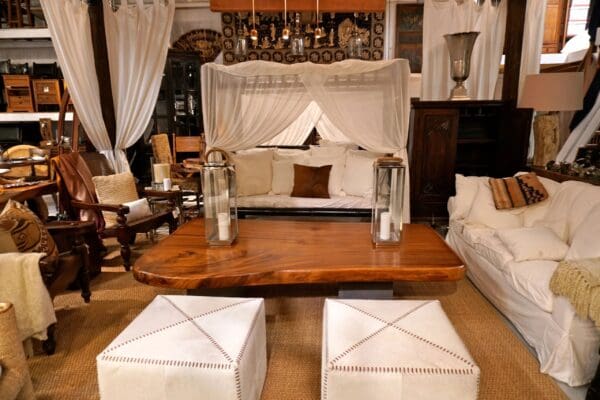 A living room with two white ottomans and a canopy bed.