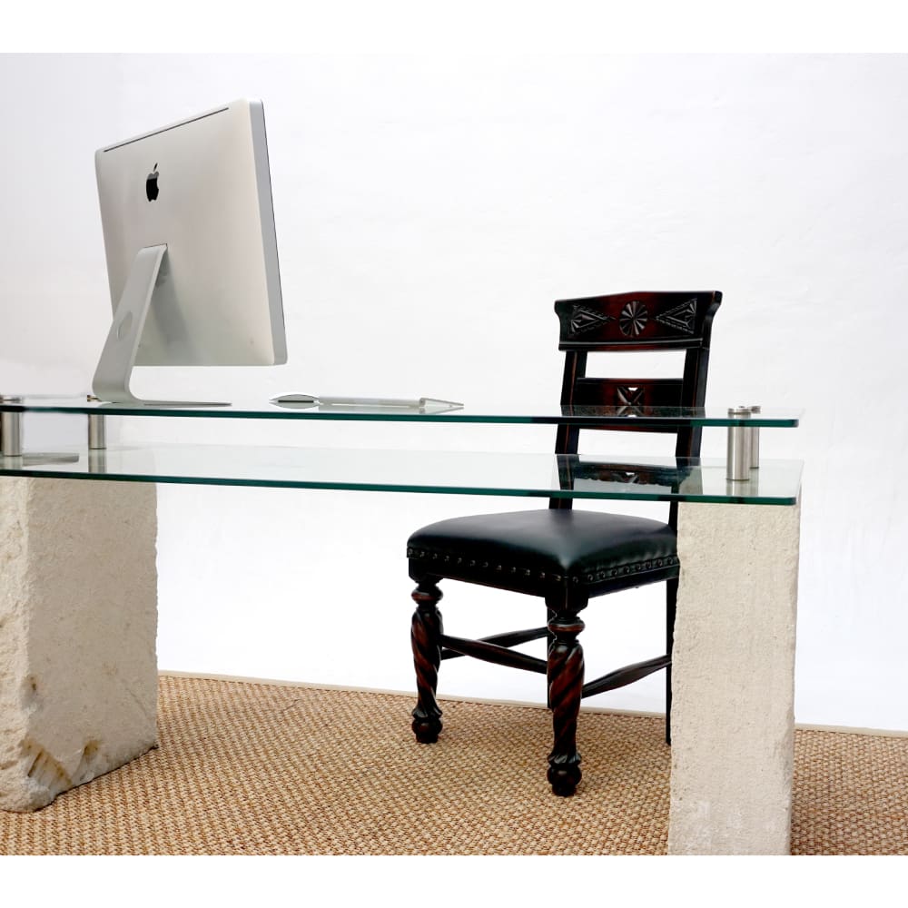 A glass desk with a chair and apple monitor