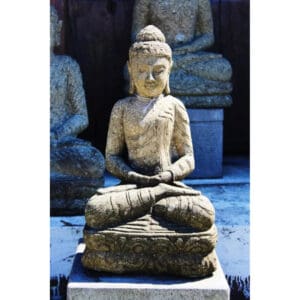A statue of buddha sitting on top of a stone slab.