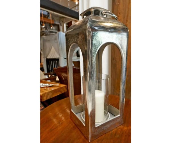 A silver lantern with candles inside of it.