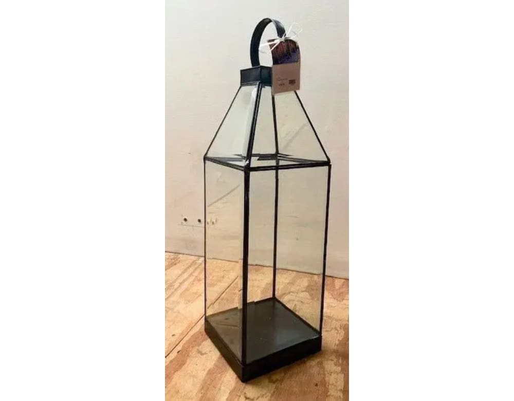 A tall glass lantern with a black metal base.