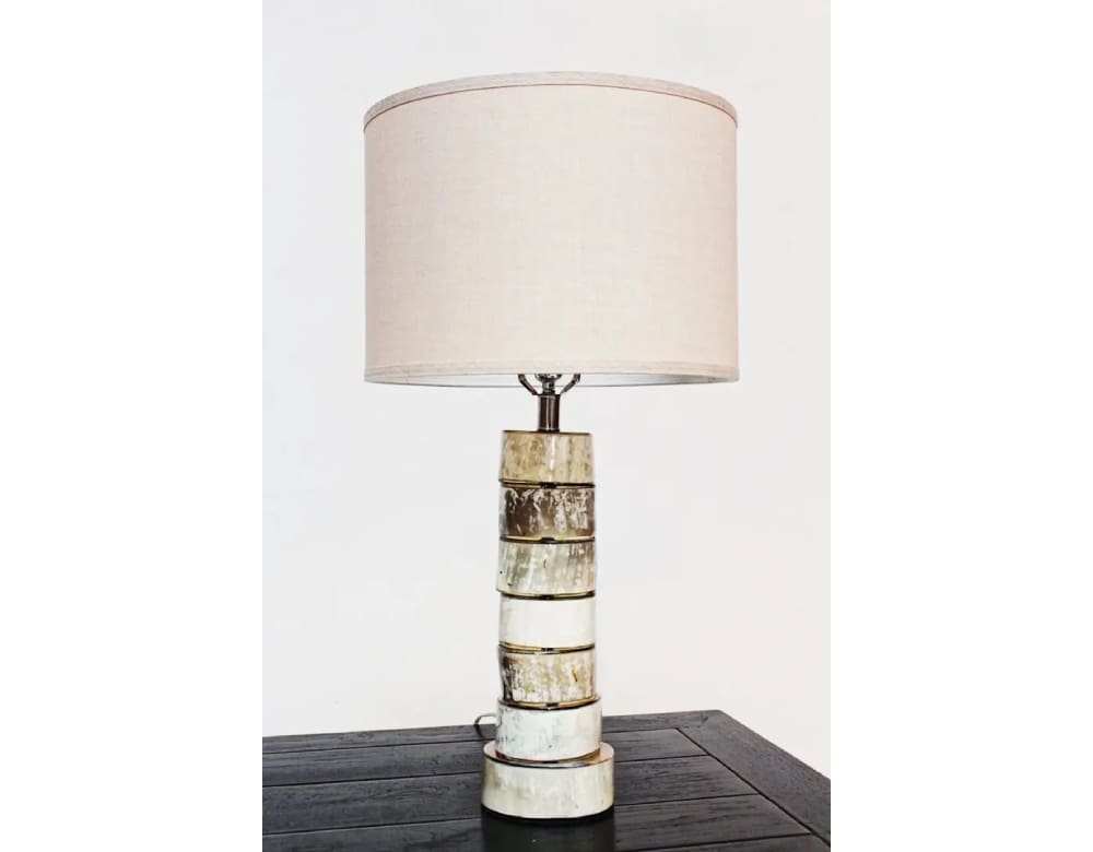 A table lamp with a white shade on top of a black table.