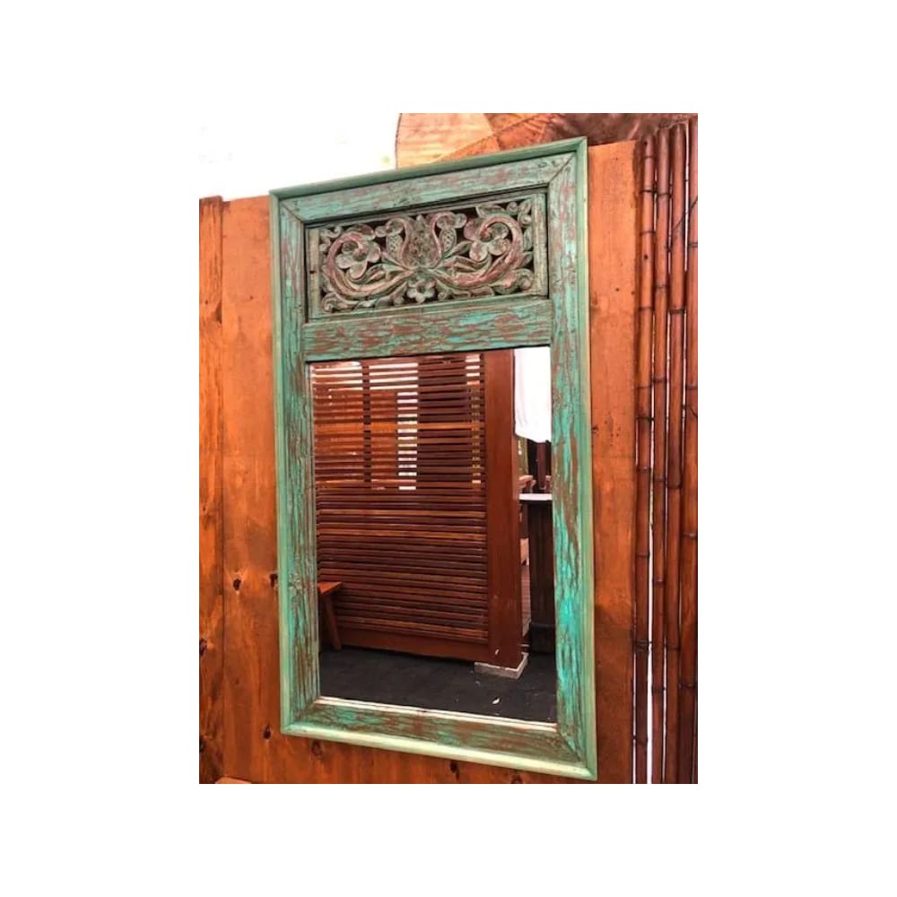 A mirror with an ornate frame on the side of a wooden wall.