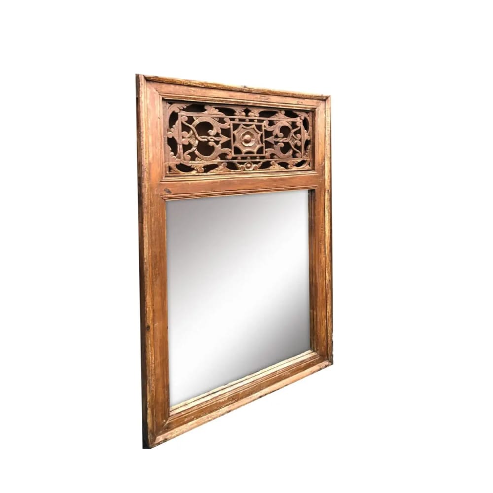 A mirror with a wooden frame and carved design.