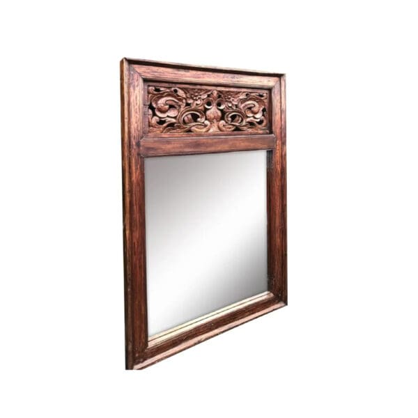 A mirror with a wooden frame and carved design.