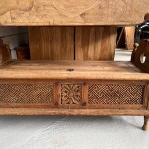 Carved wooden bench with storage and intricate design.