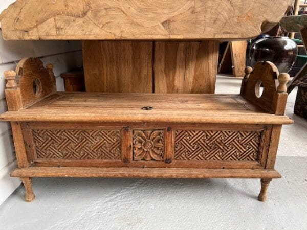 Carved wooden bench with storage and intricate design.