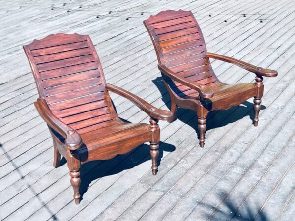 Two wooden chairs on a deck.