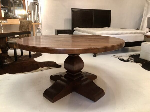 Round wood dining table with pedestal base.